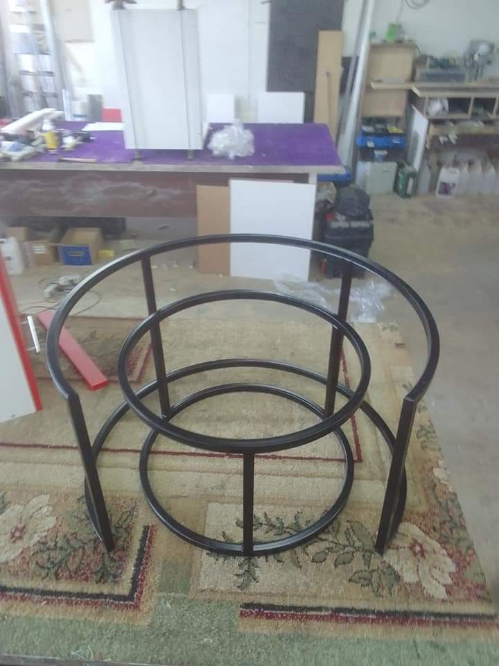 Metalowa konstrukcja stolika kawowego z okrągłymi elementami, wykonana z czarnych rurek, na dywanie w warsztacie.