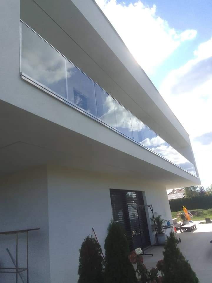 Nowoczesna balustrada ze szkła i stali nierdzewnej na balkonie w Bydgoszczy, z odbiciem chmur. Minimalistyczny design, jasne barwy.