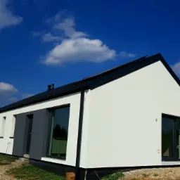 Nowoczesny, parterowy dom z białą elewacją i grafitowymi akcentami, widoczny z zewnątrz w słoneczny dzień, z czarnym dachem i dużymi oknami, otoczony gruzem.