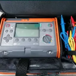 Miernik elektryczny Sonel MPI-525 w czarnym futerale z kolorowymi przewodami pomiarowymi, widoczne przyciski i wyświetlacz.