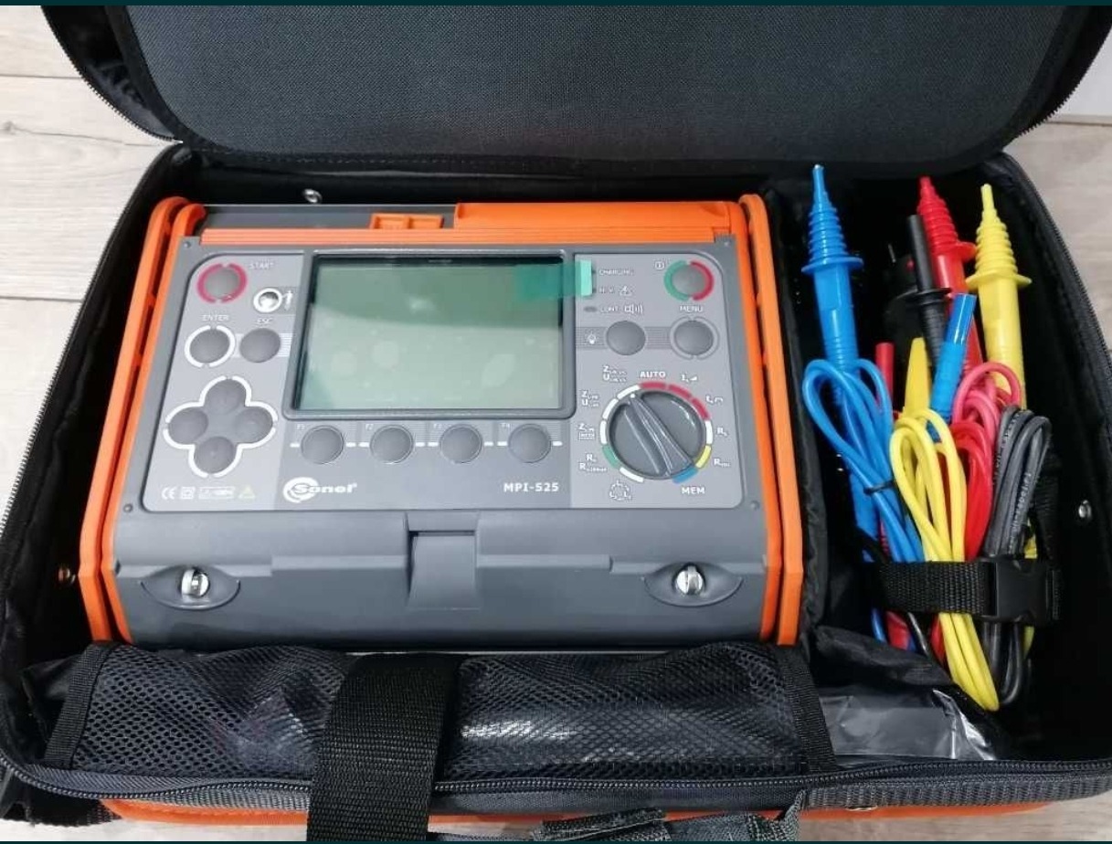 Miernik elektryczny Sonel MPI-525 w czarnym futerale z kolorowymi przewodami pomiarowymi, widoczne przyciski i wyświetlacz.