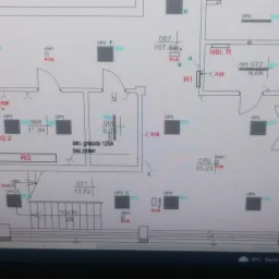 Plan instalacji elektrycznej budynku z naniesionymi punktami oświetleniowymi, gniazdami i rozdzielnicami, widoczne oznaczenia i wymiary pomieszczeń.