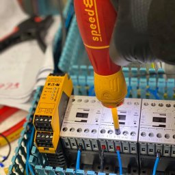 ReSet Rostyslav Batsenko - Podłączenie przewodów do styczników i modułu bezpieczeństwa Eaton w skrzynce rozdzielczej za pomocą wkrętaka Wiha SpeedE w rękawicy roboczej.