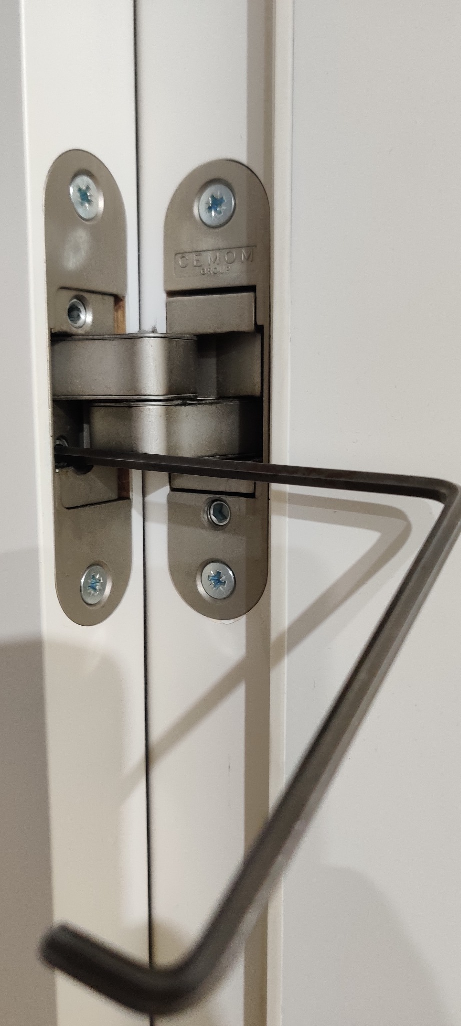 Regulacja zawiasu okiennego za pomocą klucza imbusowego, widoczny mechanizm zawiasu firmy CEMOM.