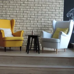 Dwa fotele typu uszak, żółty i szary, stoją na drewnianym podeście przed ścianą z cegły i tablicą z rysunkiem kredą.