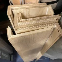 Stos wyciętych elementów drewnianych paneli podłogowych z widocznymi zamkami, oczekujących na montaż, w magazynie lub warsztacie.