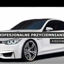 Białe sportowe auto z przyciemnionymi szybami bocznymi i tylną, prezentowane z boku na jasnym tle. Widoczne felgi aluminiowe o skomplikowanym wzorze.