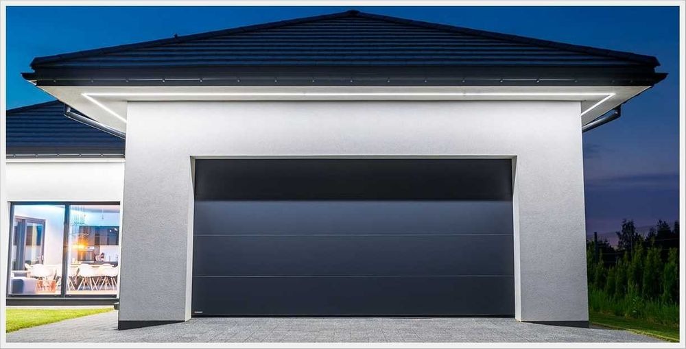 Elegancka, grafitowa brama garażowa segmentowa z oświetleniem LED w Szczecinie, zamontowana w nowoczesnym domu z dużymi oknami.