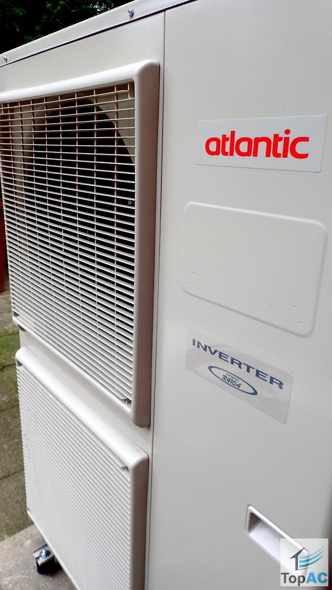 Zewnętrzna jednostka klimatyzacji Atlantic z widoczną kratką wentylacyjną, naklejką informującą o inwerterze R410A i logo firmy TopAC w prawym dolnym rogu.