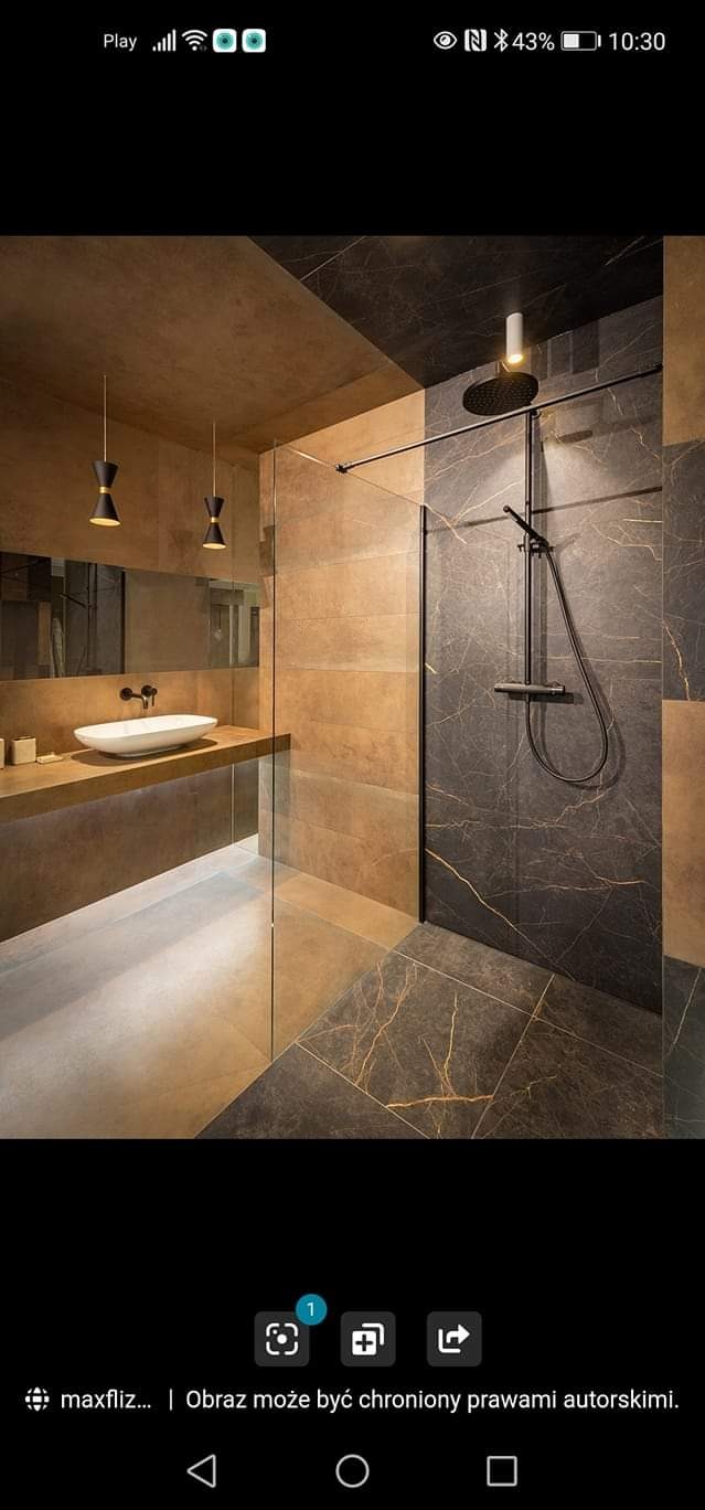 Nowoczesna łazienka z kabiną prysznicową typu walk-in, wykończona płytkami w odcieniach brązu i szarości z marmurkowym wzorem, oświetlona wiszącymi lampami o kształcie klepsydry i podświetleniem...