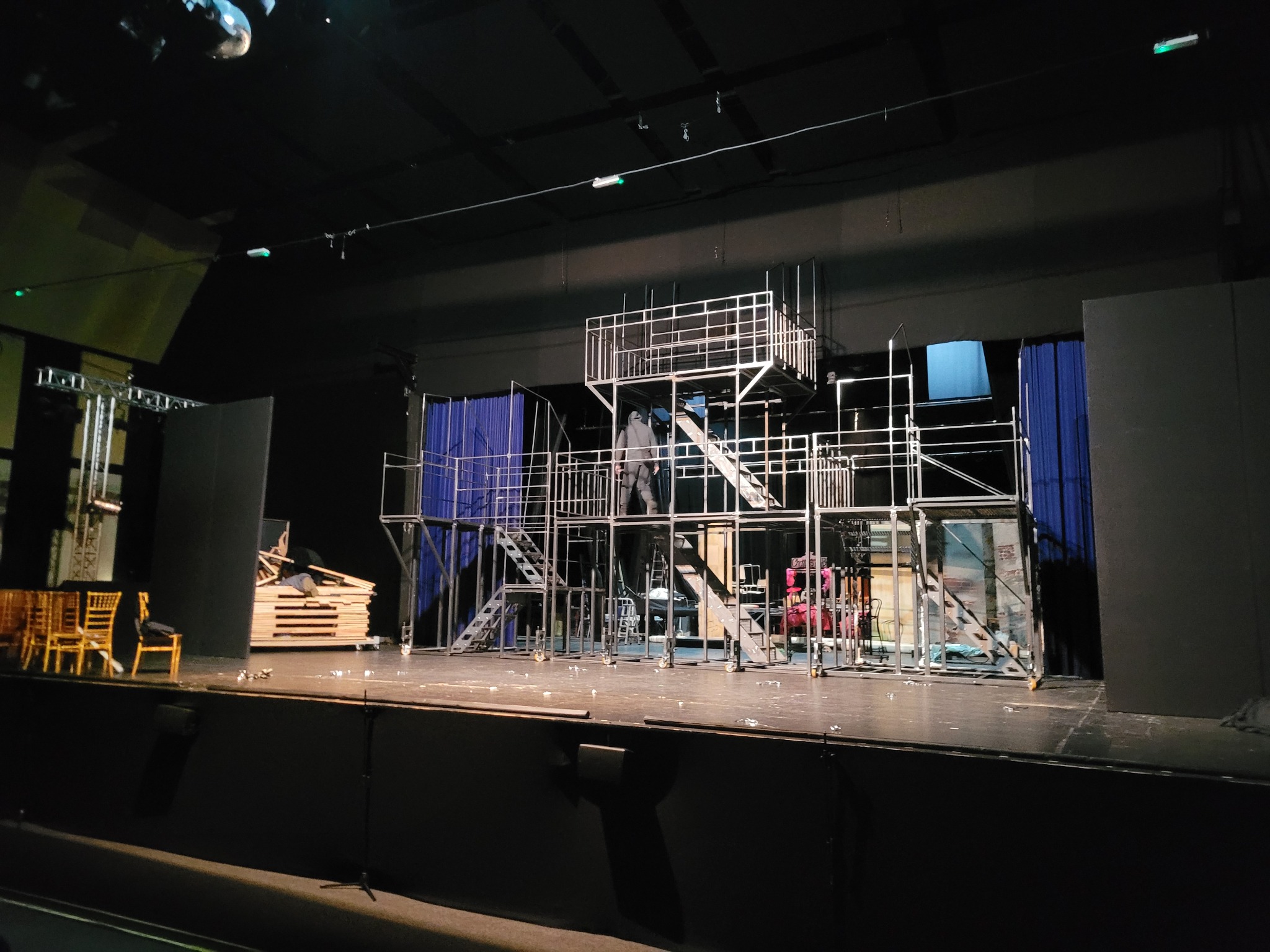 Metalowa konstrukcja sceniczna ze schodami i platformami w trakcie montażu, widoczne elementy scenografii i oświetlenie.