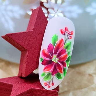 Paznokieć z ręcznie malowanym, szczegółowym wzorem kwiatu poinsecji (gwiazdy betlejemskiej) w odcieniach czerwieni i zieleni, umieszczony na czerwonej, drewnianej gwiazdce, na rozmytym tle...