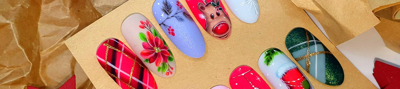 Zestaw tipsów z świątecznymi wzorami: renifer z czerwonym nosem, poinsecja, śnieżynki, kratka z brokatem, prezentowane na tekturowym podłożu.