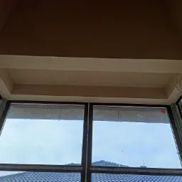 Wykończony sufit podwieszany z elementami płyty karton gips przy oknie dachowym, widoczne niedoskonałości szpachlowania na ścianach bocznych.