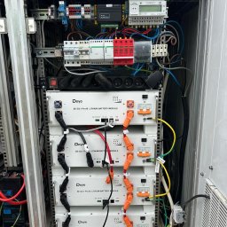 Zielona Era - Wnętrze szafy sterowniczej z modułami bateryjnymi Deye SE-G5.1 Pro-B. Widoczne okablowanie, zabezpieczenia i licznik energii. Złożona instalacja wewnątrz metalowej obudowy.