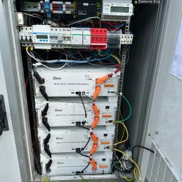 Zielona Era - Wnętrze szafy sterowniczej z czterema modułami baterii litowych Deye SE-G5.1 Pro-B, okablowaniem i elementami zabezpieczającymi. Widoczne liczniki i bezpieczniki.