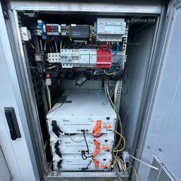 Zielona Era - Otwarta szafa sterownicza z trzema modułami bateryjnymi Deye SE-G5.1 Pro-B, licznikiem energii i zabezpieczeniami. Widoczne okablowanie i elementy instalacji elektrycznej.