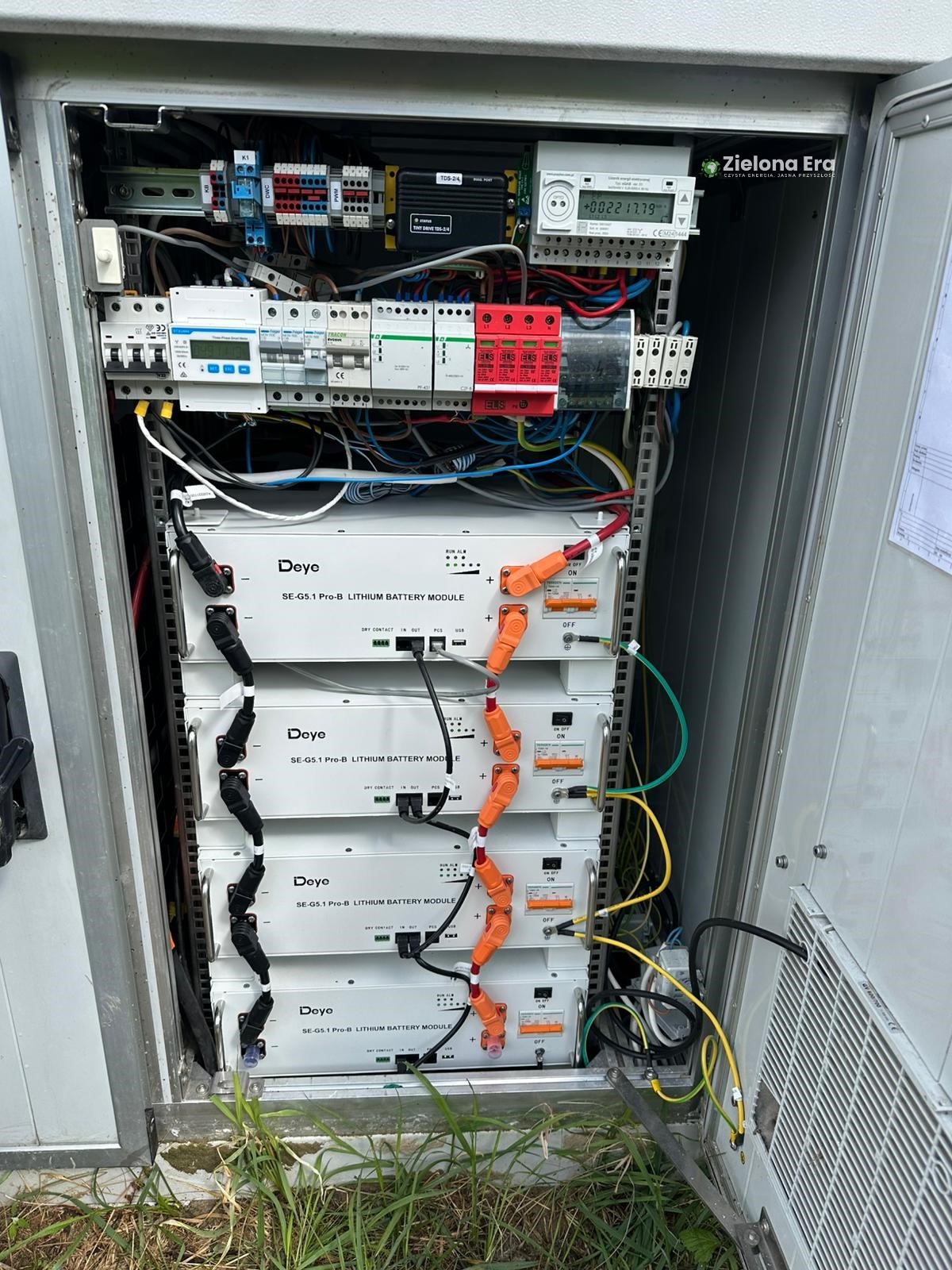 Wnętrze szafy sterowniczej z czterema modułami baterii litowych Deye SE-G5.1 Pro-B, okablowaniem i elementami zabezpieczającymi. Widoczne liczniki i bezpieczniki.