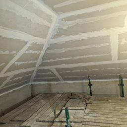 Firma remontowo-wykonczeniowa Hubert Lach - Poddasze w trakcie wykańczania płytami gipsowo-kartonowymi, widoczne łączenia płyt wypełnione masą szpachlową, ustawione rusztowanie robocze.