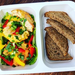 DietMeal Catering Dietetyczny - Dietetyczny posiłek w białym pojemniku: omlet warzywny z papryką i szczypiorkiem oraz trzy kromki ciemnego pieczywa na drewnianym stole.