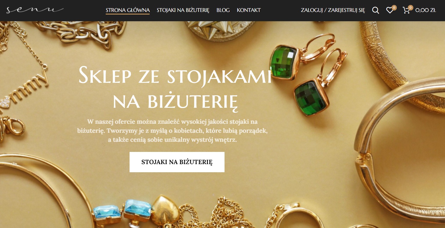 Projekt strony internetowej sklepu z biżuterią, prezentujący złote łańcuszki, kolczyki z zielonymi kamieniami i bransolety na beżowym tle, z widocznym menu nawigacyjnym i logo w lewym górnym rogu.