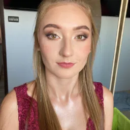 Portret kobiety z profesjonalnym makijażem oczu w odcieniach złota i brązu, podkreślonymi brwiami i delikatnymi ustami w kolorze różu, uzupełniony długimi, srebrnymi kolczykami łańcuszkowymi...