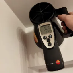 Pomiar anemometrem Testo 417 przy suficie, wskazania 3.07 m/s i 19.4 stopni Celsjusza widoczne na wyświetlaczu.