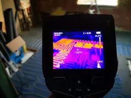 Kamera termowizyjna pokazuje rozkład ciepła na podłodze z zainstalowanym ogrzewaniem podłogowym, widoczne różnice temperatur w kolorach od fioletowego do żółtego.