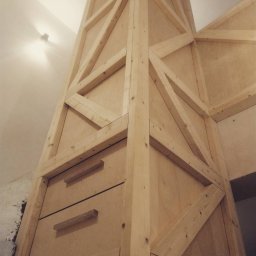 Materia Rafał Pyster - Drewniana konstrukcja antresoli z szufladami w trakcie budowy, widoczne surowe drewno i elementy mocujące.