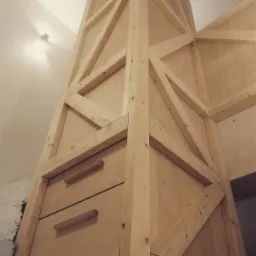 Drewniana konstrukcja antresoli z szufladami w trakcie budowy, widoczne surowe drewno i elementy mocujące.