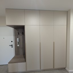 Fado Wood - Beżowa szafa wnękowa z siedziskiem i wieszakami, zintegrowana z przedpokojem. Minimalistyczny design, złote uchwyty, drewnopodobne wykończenie wnęki.