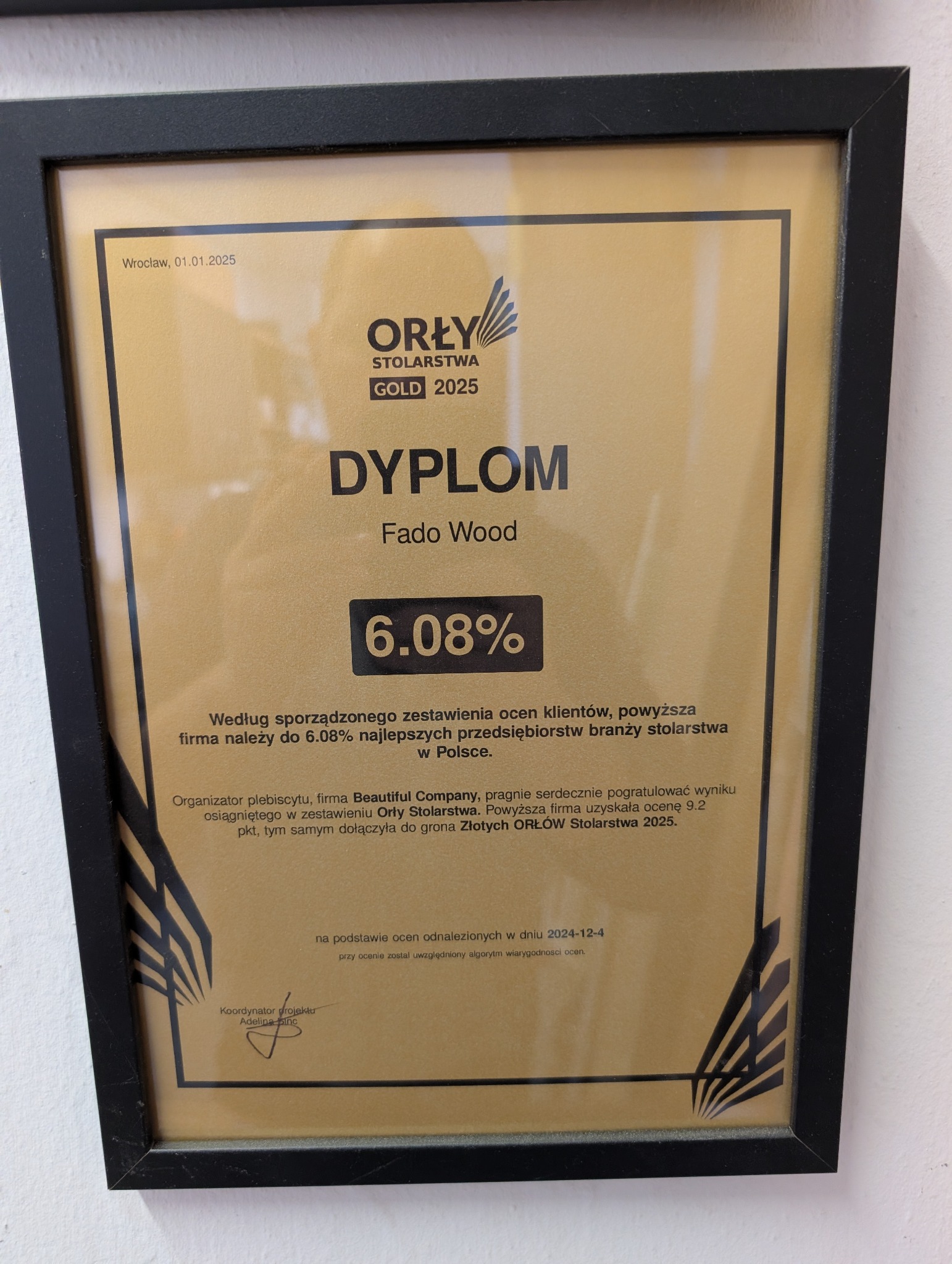 Dyplom 'Orły Stolarstwa Gold 2025' dla Fado Wood, potwierdzający przynależność do 6.08% najlepszych firm stolarskich w Polsce. Czarna ramka, złote tło dyplomu.