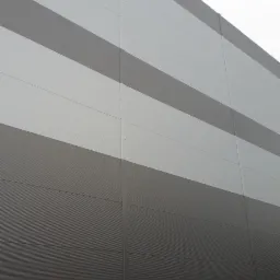 Fasada budynku przemysłowego z szarych i białych płyt warstwowych, widok z dołu pod kątem.