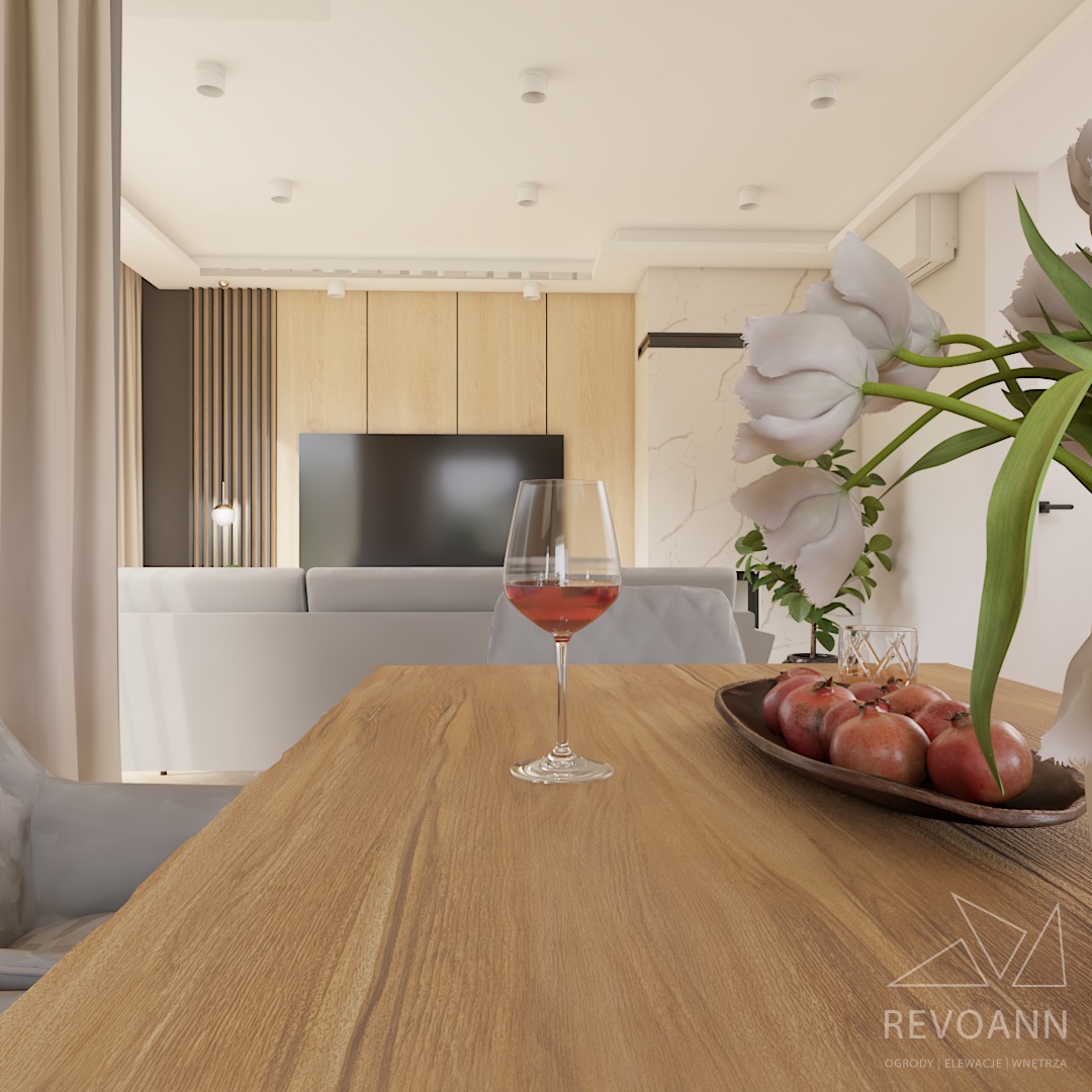 Wnętrze salonu z drewnianym stołem, kieliszkiem czerwonego wina i dekoracyjnym naczyniem z owocami, w tle telewizor i jasna sofa, widoczne logo firmy REVOANN.