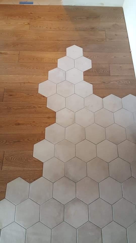 Układanie heksagonalnych płytek podłogowych w łazience, częściowo ukończone, z widocznym przejściem między drewnianą podłogą a płytkami.