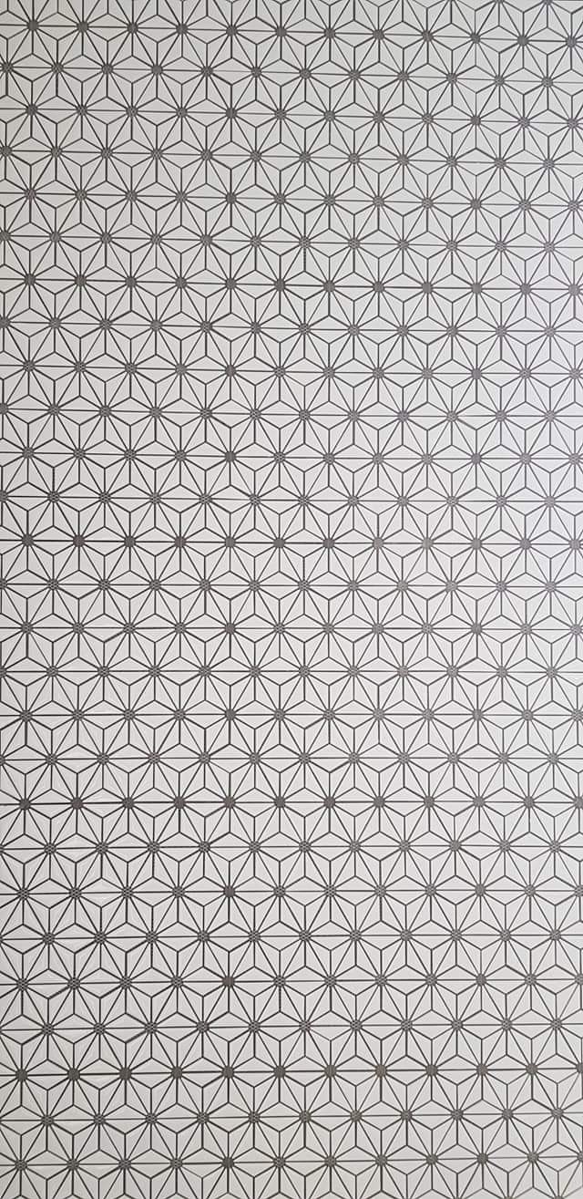 Geometryczny wzór płytek w odcieniach szarości i bieli, ułożonych w powtarzalny motyw gwiazdy trójkątnej, zrealizowany w Warszawie.