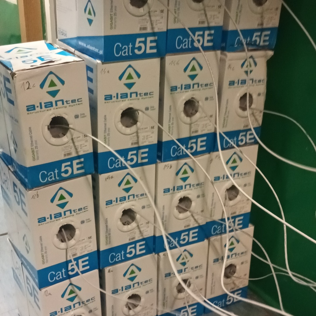 Stos kartonowych pudełek kabli Ethernet Cat 5E marki a-lantec, z widocznymi końcówkami kabli wychodzącymi z otworów w pudełkach.