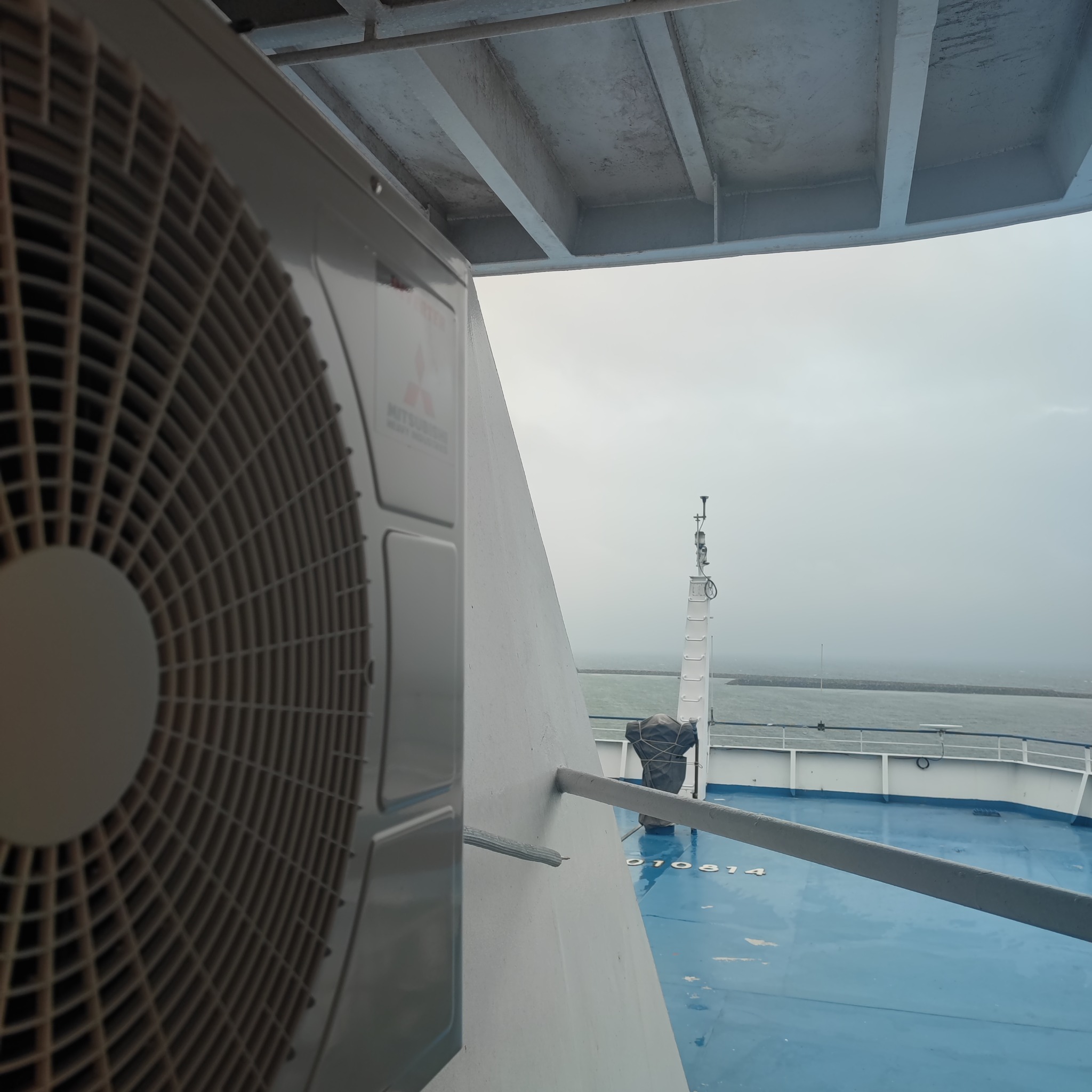 Klimatyzator Mitsubishi na pokładzie promu, widok na morze w tle, pochmurny dzień.