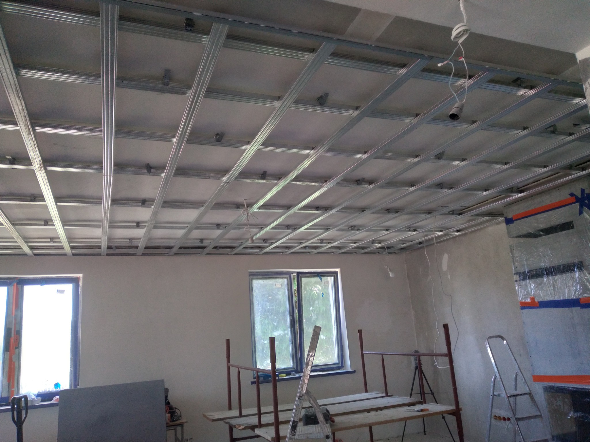 Montaż metalowej konstrukcji sufitu podwieszanego z płyt kartonowo-gipsowych w Lubawie, widoczne profile i zawiesia, przygotowanie do dalszych prac wykończeniowych.