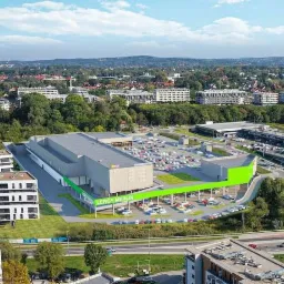 Wizualizacja z lotu ptaka budynku handlowego Leroy Merlin z parkingiem, otoczonego zabudową miejską i zielenią.