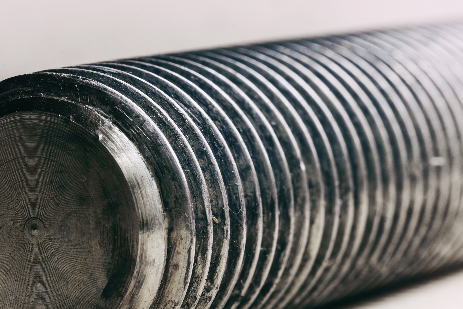 Metalowy wałek z precyzyjnie wykonanymi, regularnymi żłobieniami, widoczne ślady obróbki skrawaniem.
