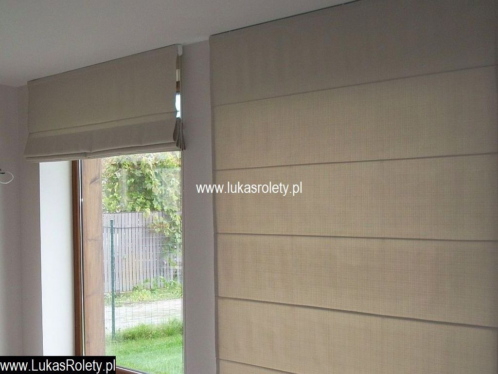 Beżowe, tekstylne zasłony panelowe w oknie, widok na ogród za oknem.