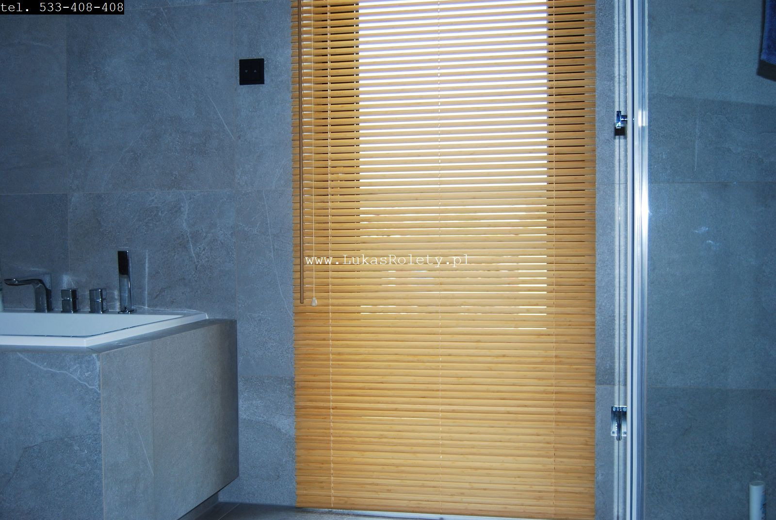 Jasne, drewniane lamele w łazience z szarą armaturą i kabiną prysznicową, widoczny adres strony internetowej na produkcie.