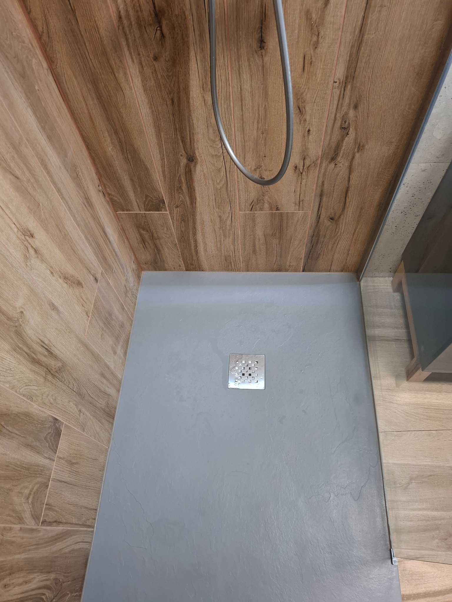 Nowoczesna kabina prysznicowa z odpływem liniowym i drewnopodobnymi płytkami na ścianach, widok z góry.