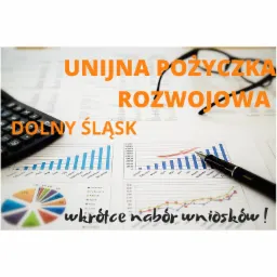 Kalkulator, okulary i pi&oacute;ro na tle dokument&oacute;w z wykresami słupkowymi i kołowymi, informacja o unijnej pożyczce rozwojowej dla Dolnego Śląska i zbliżającym się naborze wniosk&oacute;w.