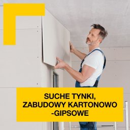 Piotr Szczepanek - Monter w niebieskim kombinezonie, z profilu, instaluje płytę gipsowo-kartonową na ścianie w pomieszczeniu z surowym betonowym sufitem; widoczna drabina. Częściowo wykończona ściana obok...