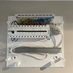 Otwarta skrzynka bezpiecznikowa z widocznymi przewodami i bezpiecznikami marki Schneider Electric, zamontowana na ścianie w Szczecinie. Widoczne detale montażu i podłączenia.