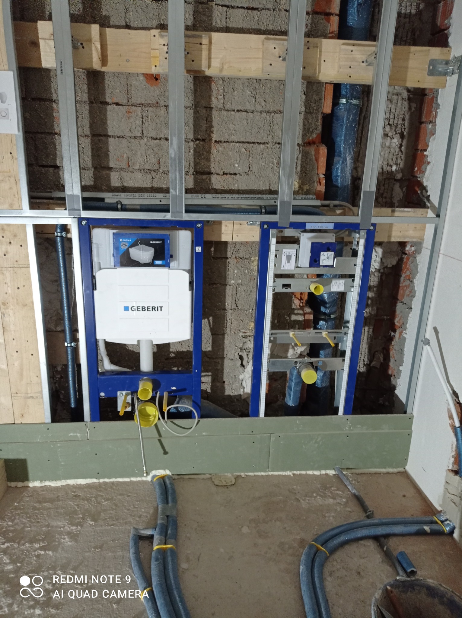 Montaż podtynkowych stelaży WC firmy Geberit w trakcie prac hydraulicznych w Białymstoku, widoczne rury i konstrukcja nośna.