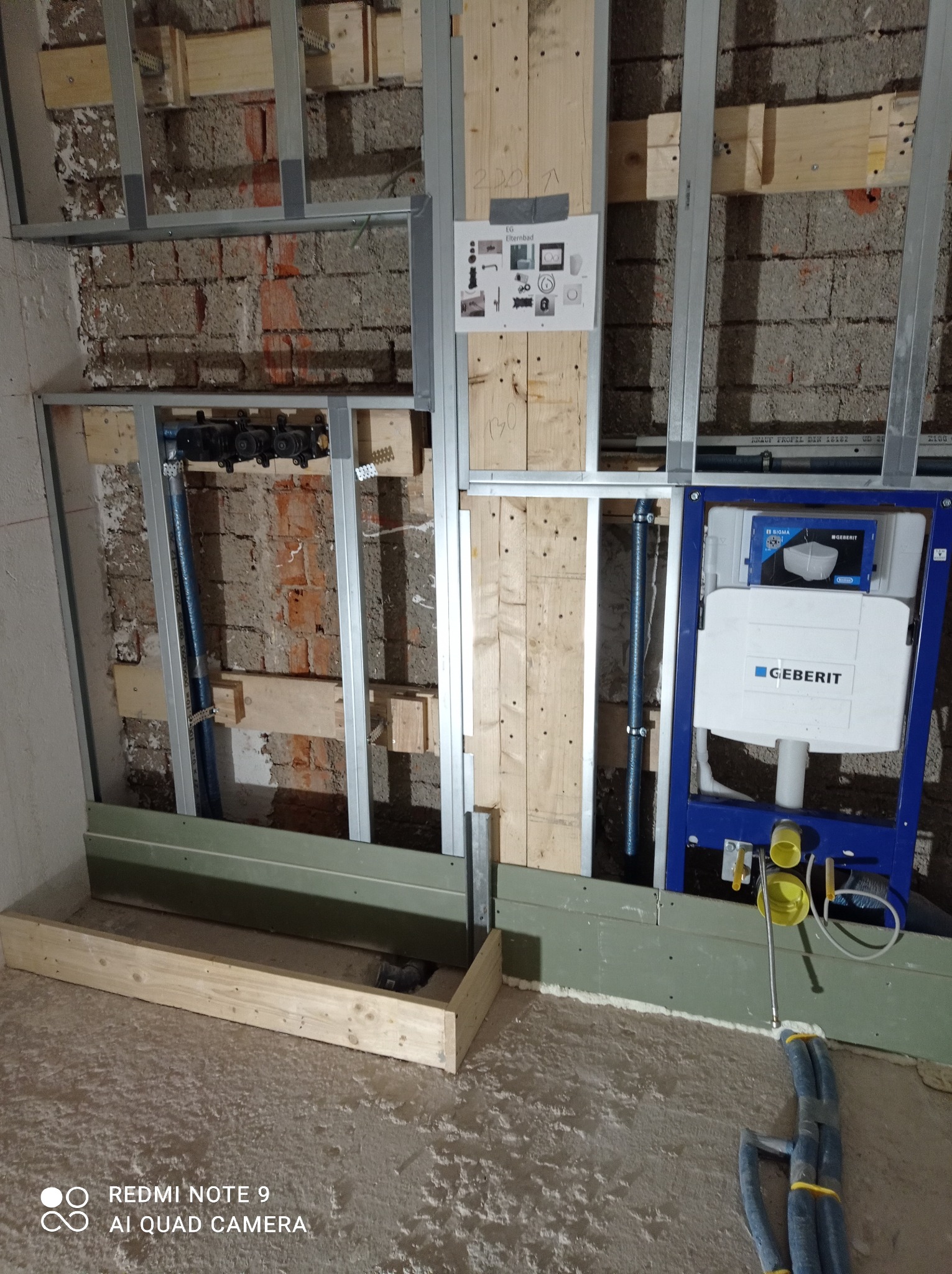 Stelaż podtynkowy Geberit zamontowany w trakcie prac hydraulicznych, widoczne rury, profile metalowe, drewniane wzmocnienia, ściana w trakcie remontu, instalacja przed zabudową.