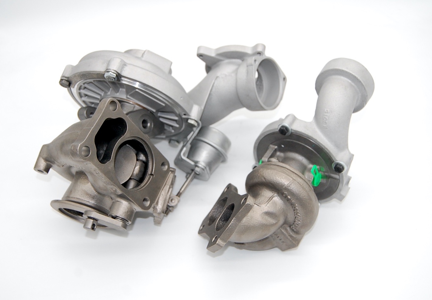Cztery turbosprężarki samochodowe, dwie w odcieniach szarości i dwie srebrne, ułożone na białym tle, z widocznymi detalami konstrukcyjnymi.